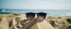 Photo de lunettes de soleil dans le sable avec vue sur la mer