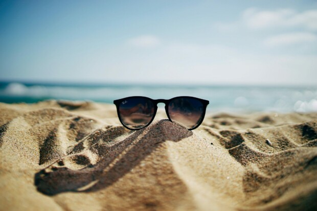 Photo de lunettes de soleil dans le sable avec vue sur la mer
